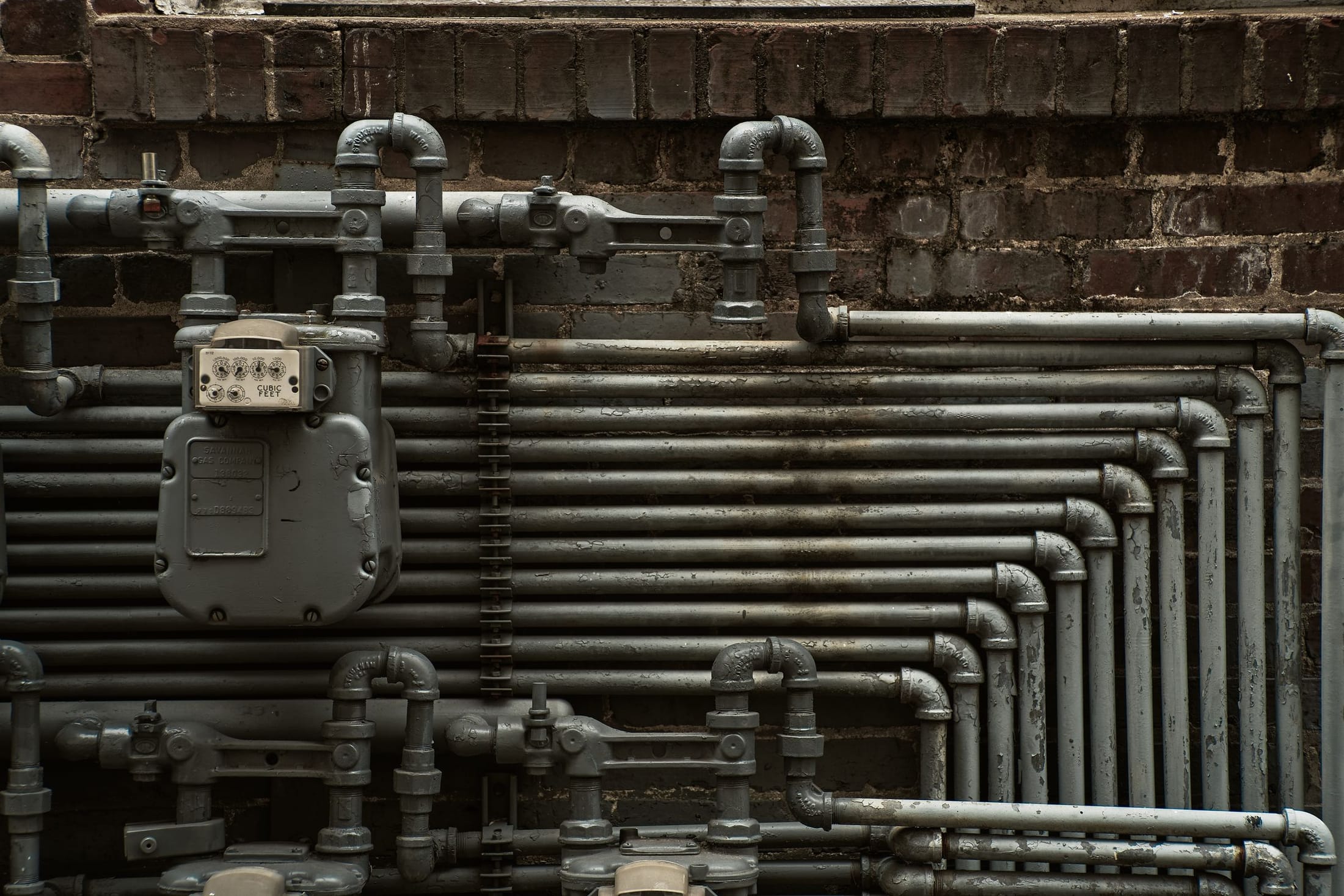 Dense bundle of process pipework running along an industrial wall