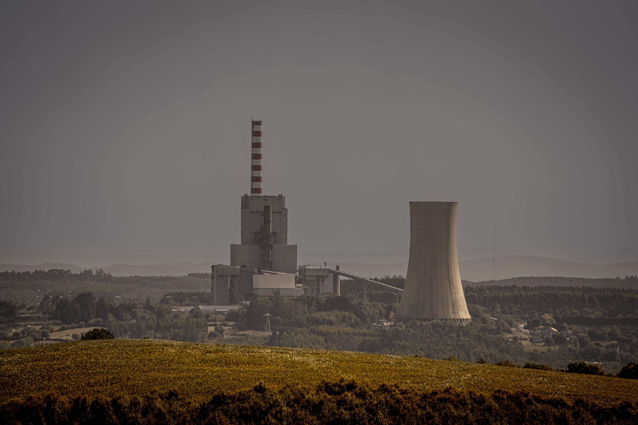 Industrial plant with cooling tower seen across open landscape
