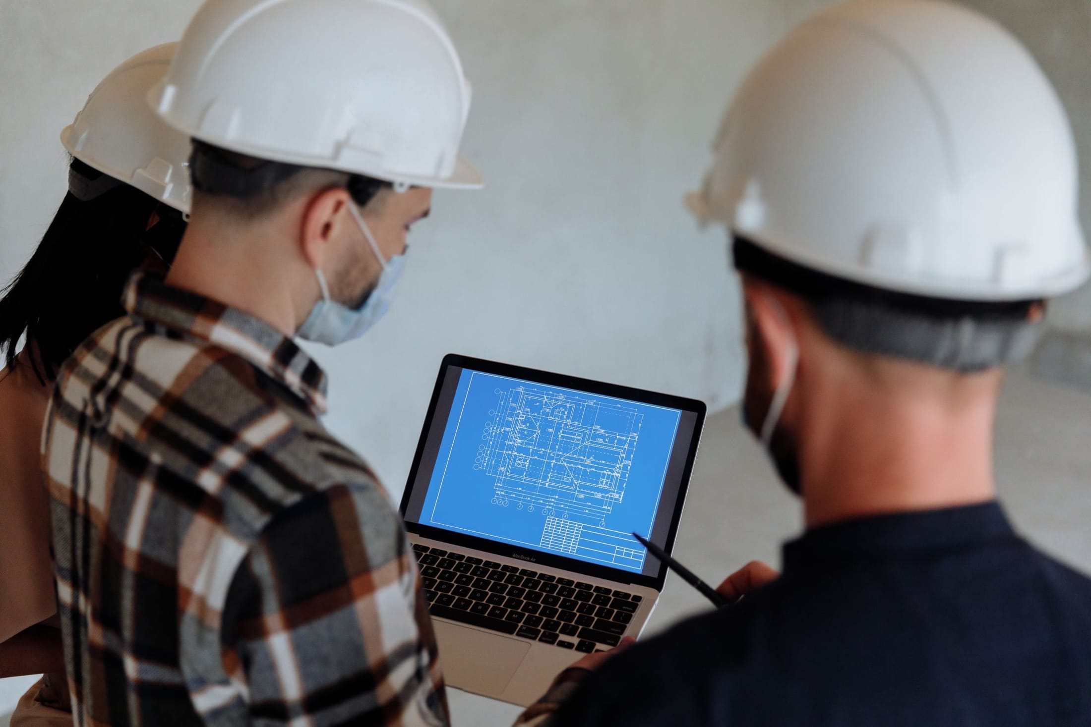 Two technical staff in hard hats reviewing information on site