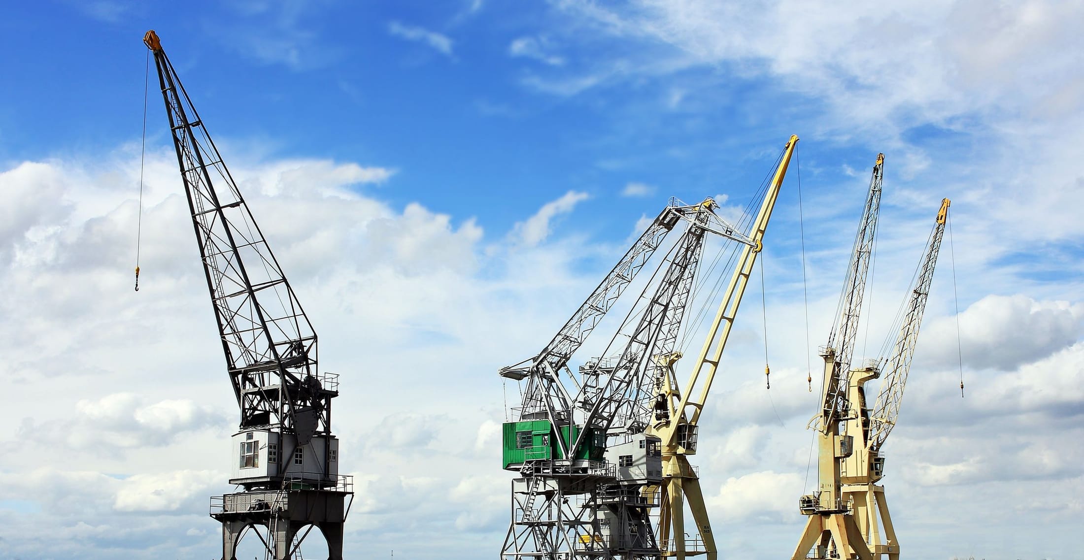 Row of heavy lifting cranes against an open sky